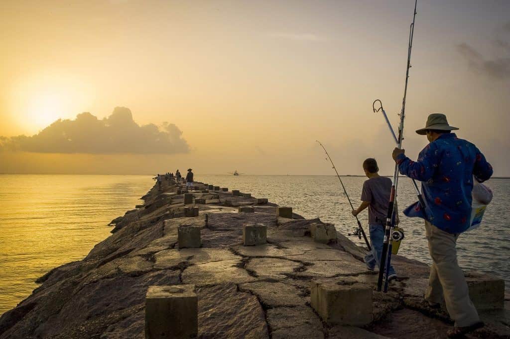 Father and son fishing at sunrise on jetty